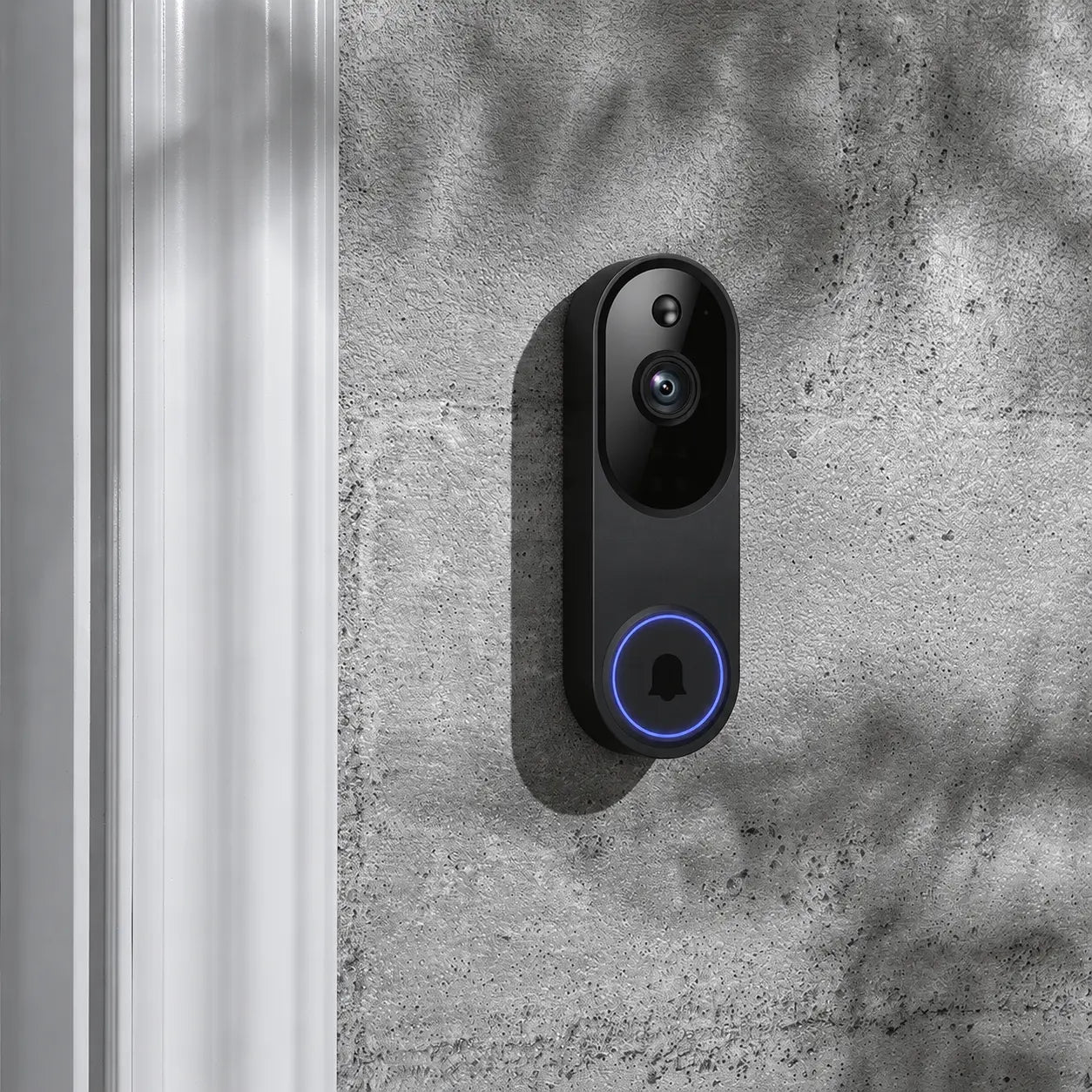 A black smart video doorbell with a blue illuminated ring around the button, mounted on a textured gray concrete wall next to a white door frame.